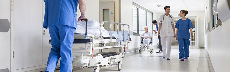 Pasillo de hospital con personal sanitario trasladando pacientes.